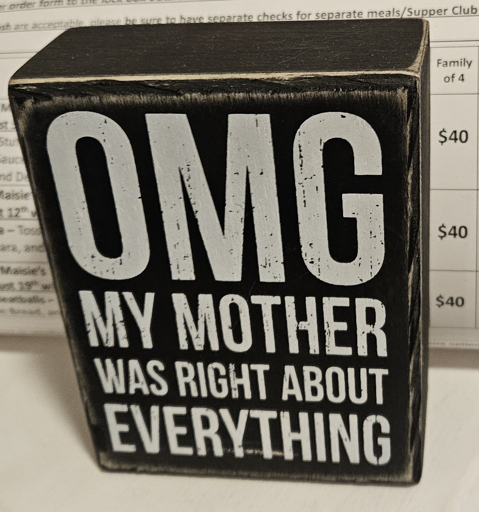 A small wooeden sign reading "OMG MY MOTHER WAS RIGHT ABOUT EVERYTHING"